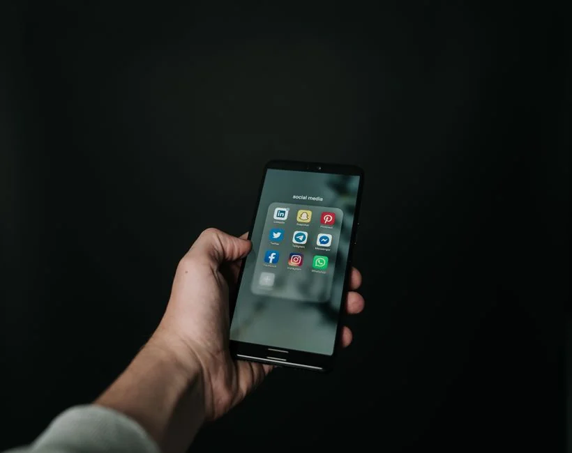 Une personne analyse des données boursières avec un smartphone et un ordinateur portable, à l’intérieur.